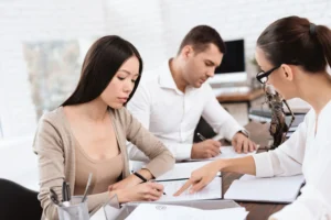 Separating couple reviewing and signing a separation agreement with a lawyer during a collaborative family law meeting.